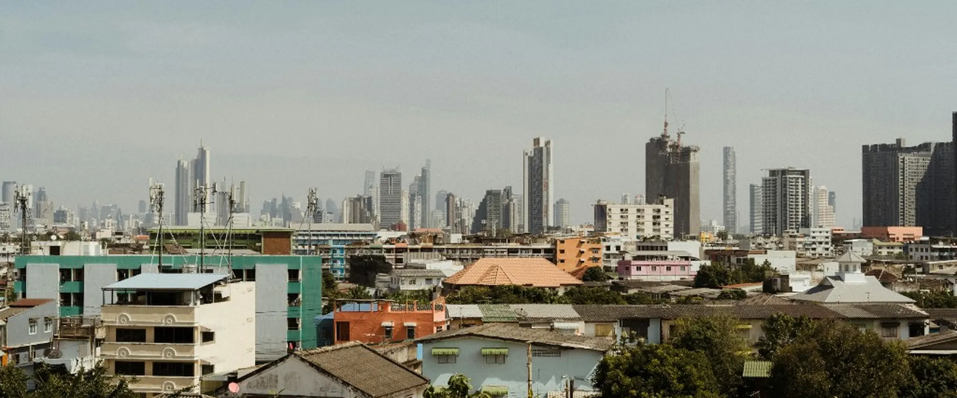 Panama City skyline beyond a neighborhood of low-rise rooftops and trees